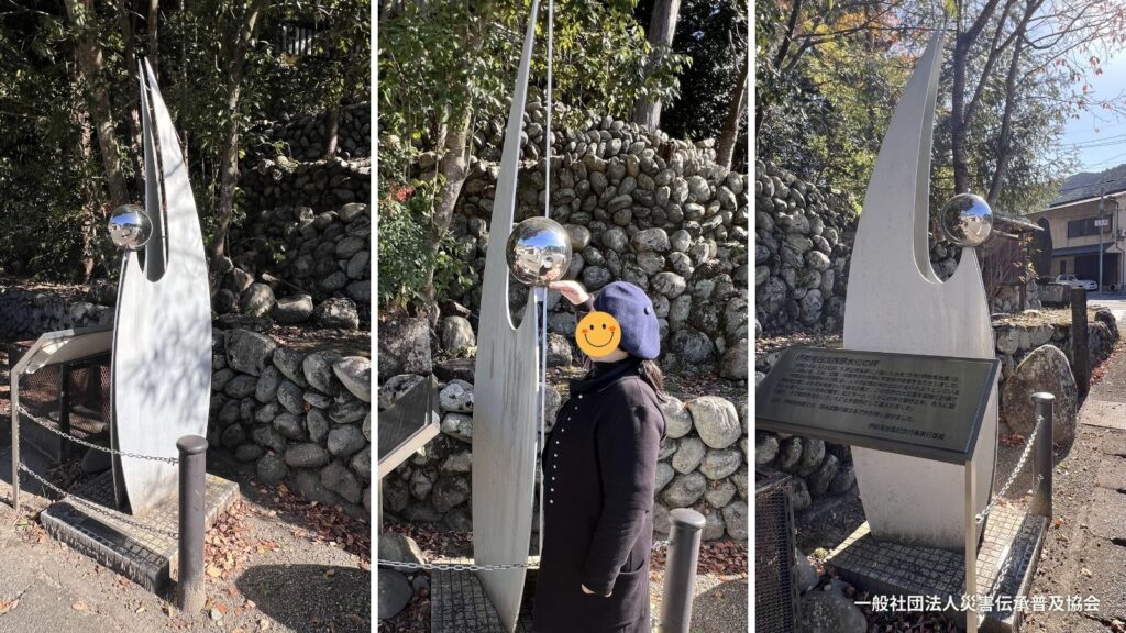 奈良県吉野郡吉野町にある自然災害伝承碑「伊勢湾台風跡水位の碑」と、碑の横で立っている女性の写真です。碑についている球体の底面まで浸水した水位が女性の身長よりも高いことがわかります。